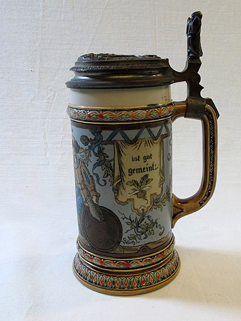 IncisedMettlach Stein #1932: Mettlach stein #1932. .5L, 9" including thumb rest. Features two gentlemen drinking together. Pewter lid. In German: A drink with a friend is a good idea!