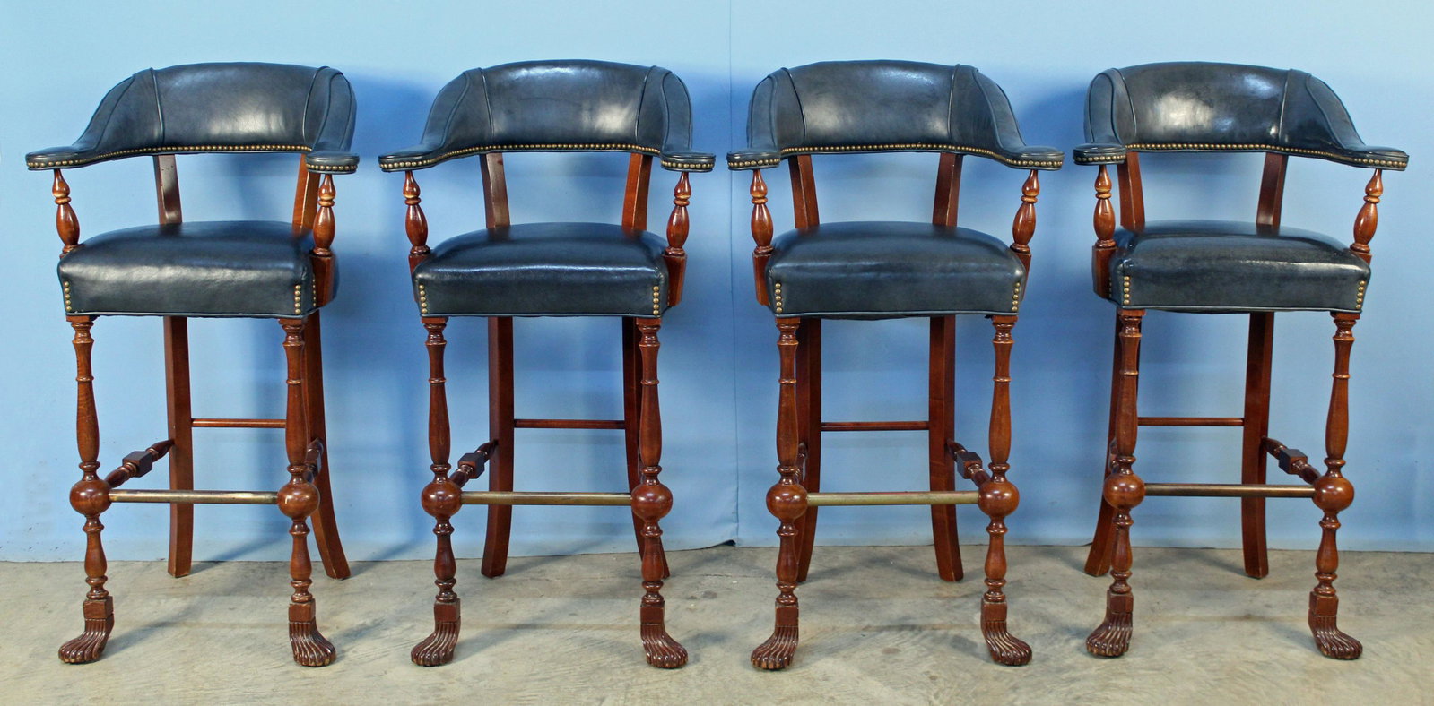 Four Bar Stools with Leather and Mahogany Finish: Four Bar Stools with Leather and Mahogany Finish. The stools have turned legs, paw feet, decorative brass tacks, brass foot rail and leather back and seat. Measure 43" High X 25" Wide X 20" Deep X App