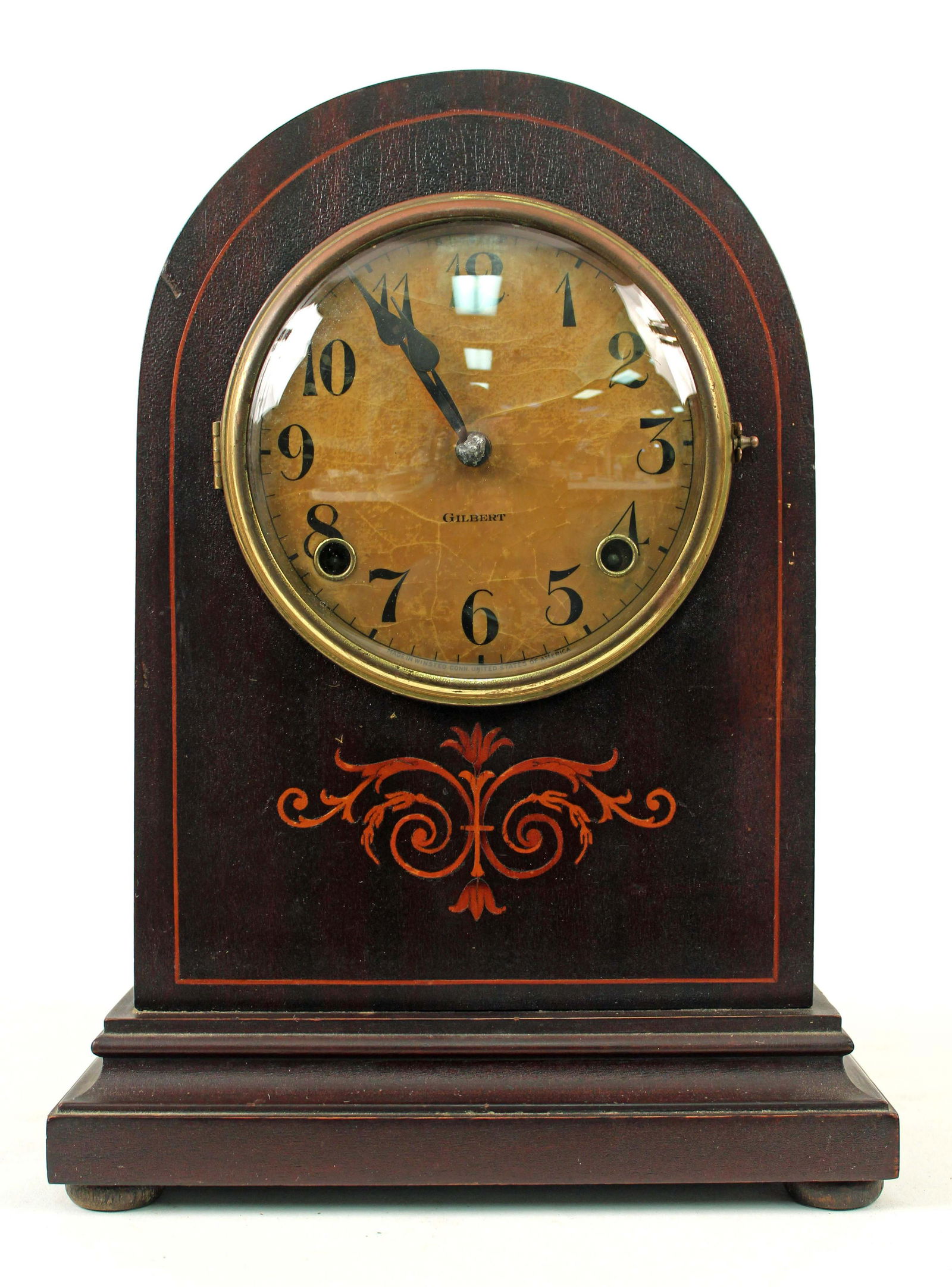Gilbert Inlaid Mahogany 8 day Mantle Clock: Gilbert Inlaid Mahogany 8 day Mantle Clock. The time and strike clock comes with key and pendulum. Measures 13" H. X 9" W. Condition - The clock was running at inventory. The case is in old finish. Wo