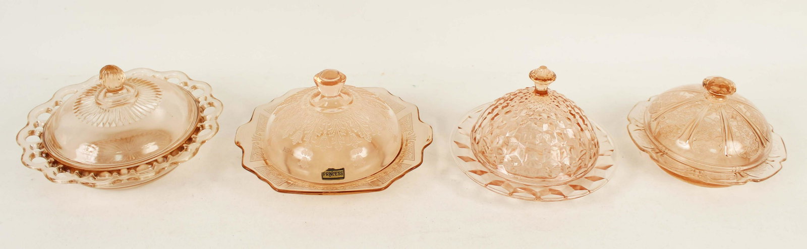 Four Pink Depression Glass Butter Dishes: (1) Cherry Blossom, Jeannette Glass Co. 1931 - 1938., pink butter dish, 4" High X 6" Dia. (1) Cubist pattern, pink butter dish, 4 1/2" High X 6 1/2" Dia. (1) Lace Edge pattern, pink butter dish, 4 1/4