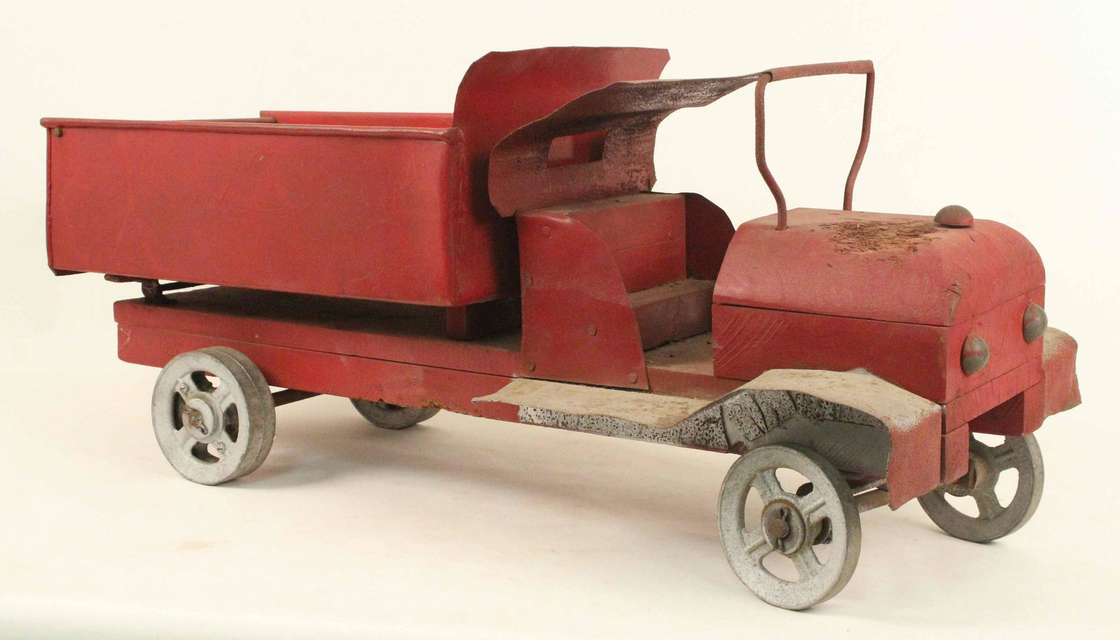1920's Handmade Dump Truck w/ Cast Iron Wheels: 1920's Handmade Dump Truck with Cast Iron Wheels. Frame, seat, motor area and hood are wood. Steel bed hand tilts and dumps with swing-out tailgate. Measures 14 1/2" High X 32 3/4" Long X 12 5/8" Wide