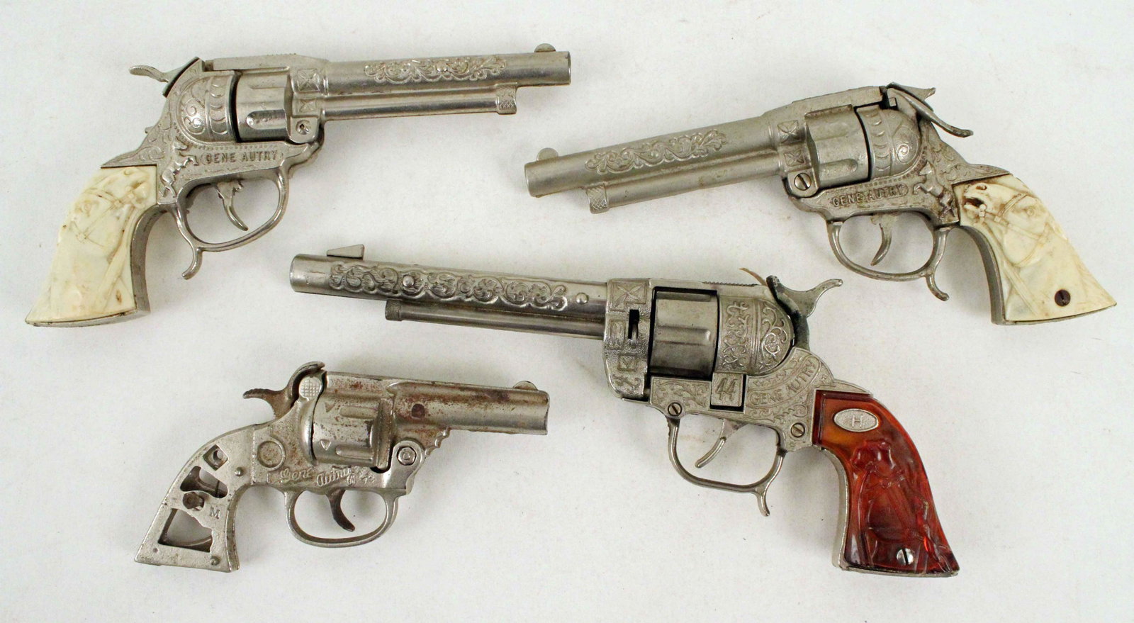 Four Gene Autry Cap Gun Pistols: Four Gene Autry Cap Gun Pistols. (1) Hubley .44 pistol with amber horse head grips. (1) Kenton cast iron cap gun. (2) Pair of Leslie Henry pistols with horse head grips. Condition- Base of amber grips