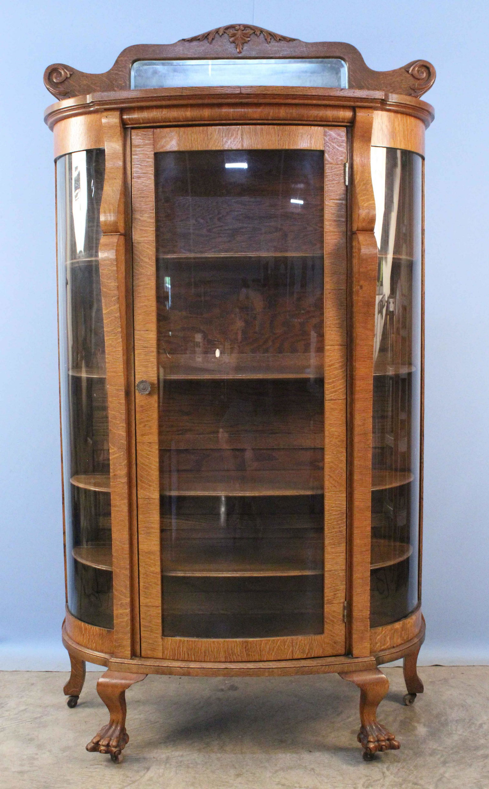 Oak Curved Glass China Cabinet w/ Claw Feet: Oak Curved Glass China Cabinet, Claw Feet, Beveled Mirror and Four Wood Shelves with Plate Grooves. This cabinet does not come with a lock or key. Measures 75 3/4" high X 42 5/8" wide X approx. 18" de