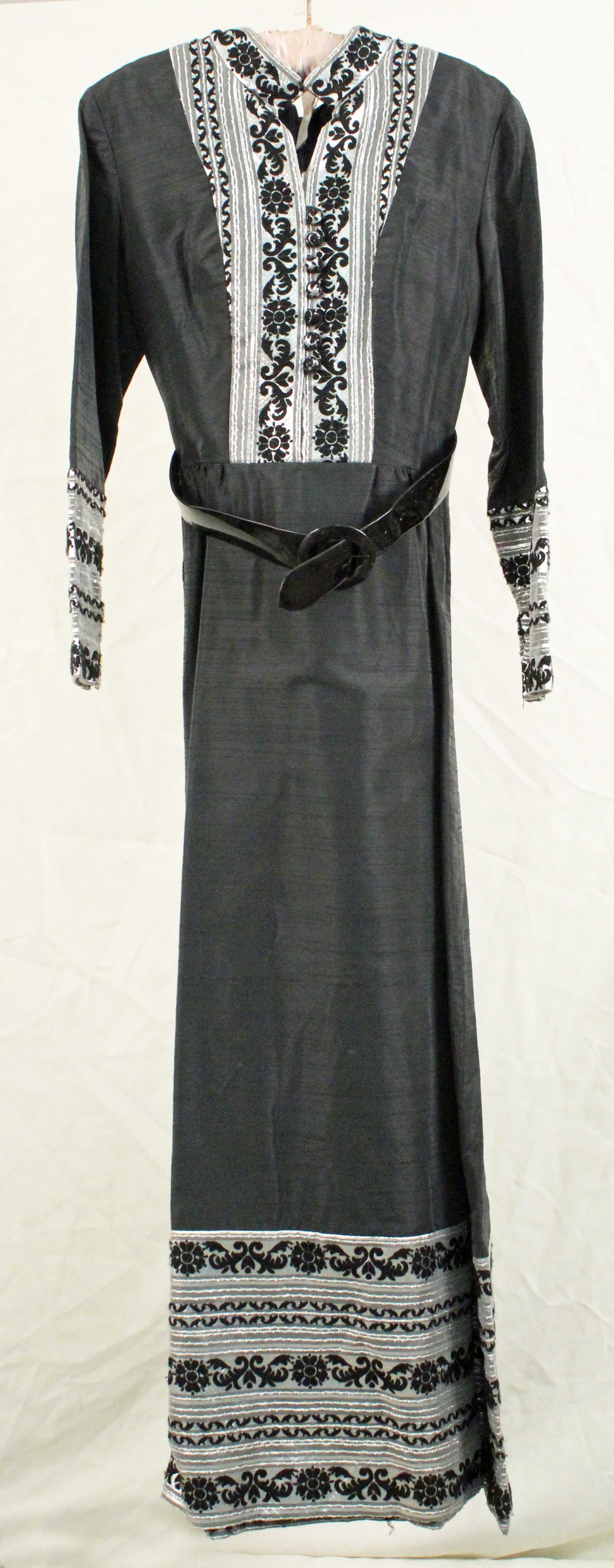 Mikla Black Shantung Silk Gown w/ Silver Brocade: Mikla Long Black Shantung Silk Gown w/ Silver Brocade Inserts, Cuff and Hem Boarders. Nice gown with standup collar and front button detail. Comes with a wide black patent leather belt, measures 34" l
