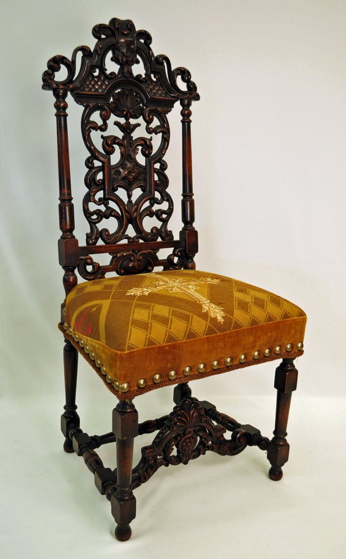 Antique Jacobean-Style Carved Walnut Side Chair: Antique Jacobean-Style walnut side chair with lavishly pierce carved back and stretcher. Covered in brass tacked, middle ages style cross material. Measures 48" H. X 22" W. X 19" D.