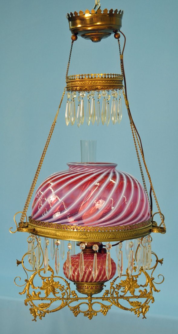 Victorian Cranberry Opalescent Light Fixture: Victorian hanging light in pierced brass frame with cranberry opalescent swirl font and shade. Shade measures 14" dia X 7" H. and 36" high overall.