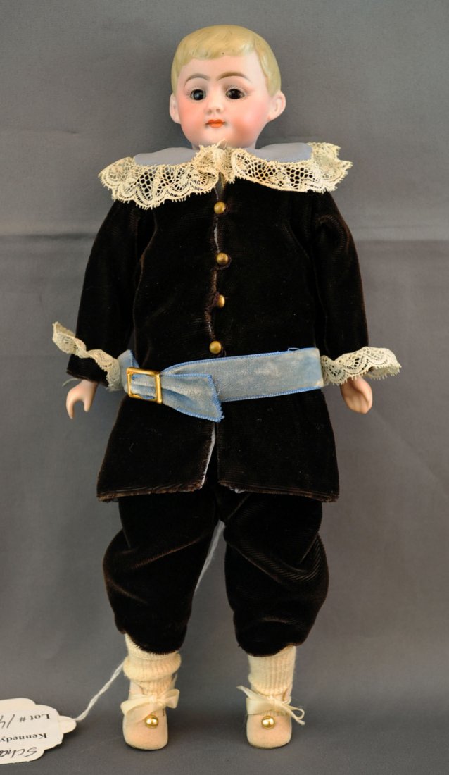 10.5" German Bisque Head American School Boy Doll: 10.5" German Bisque Head And Shoulder American School Boy Doll. Doll has closed mouth, painted eyes, brown velvet suit trimmed with lace, and a cloth body.