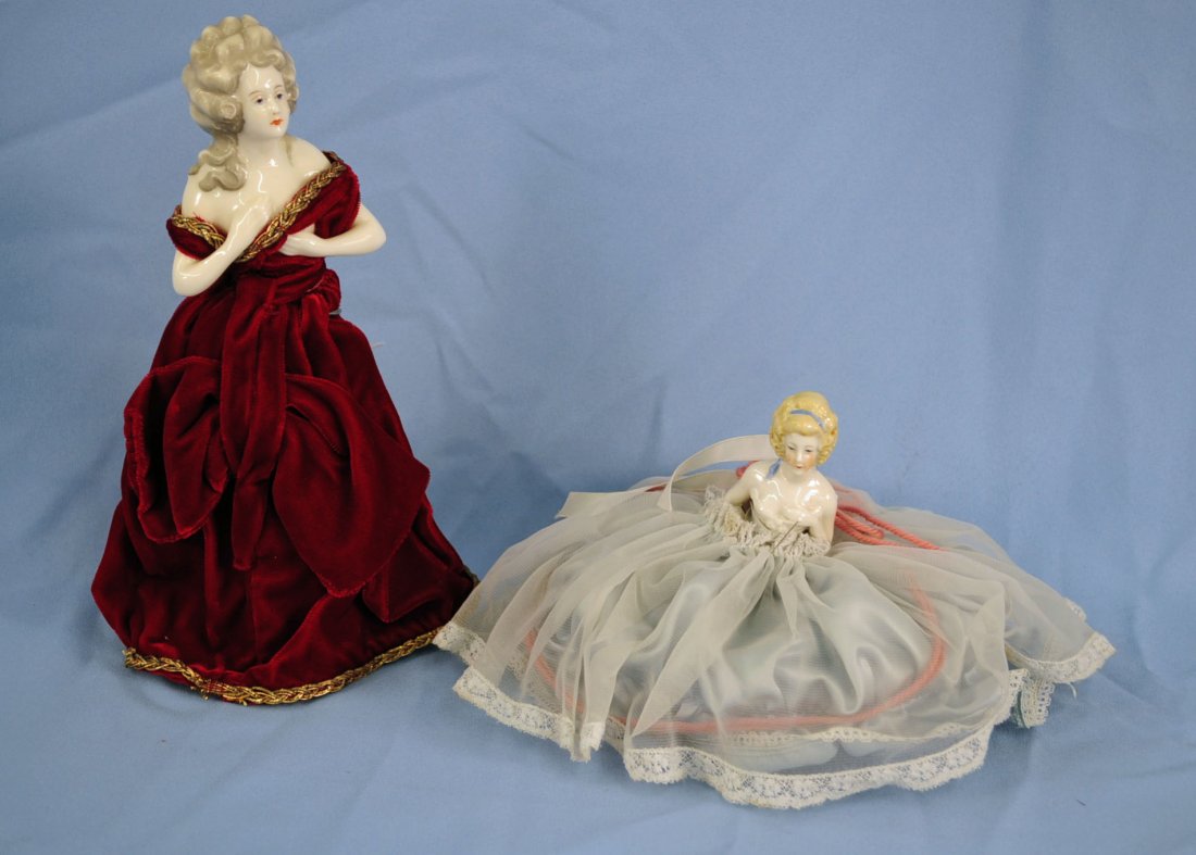 Two German Porcelain Pin Cushion Half Dolls: Two German Porcelain Pin Cushion Half Dolls. One Doll is 4.5" high with a red velvet dress and a bottle body filled with sand. Second doll is a pin cushion type, 5" high. Pin Cushion has 9" dia.