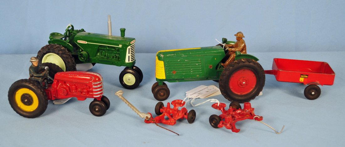 3 Toy Tractors w/ 4 Piece Oliver Set: 3 Toy Tractors w/ 3 Piece Oliver Set Includes two green Oliver tractors, and one red tractor with two trailers and one hay cutter. Condition - all noticeably played with, with some paint chips, and we