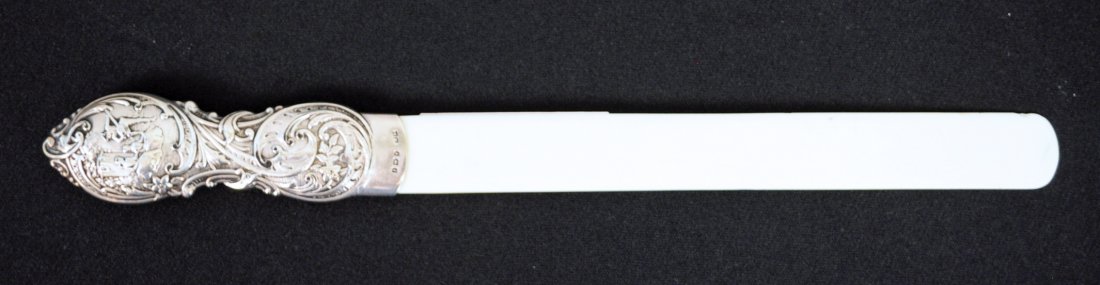 English Repose Silver-Handled Paper Knife: An English paper knife on a 5" silver handle with hallmarks and bearing a repose scene of an Englishman tuning a lute for maidens in a courtyard. Overall length of 14". - Condition: Good condition.