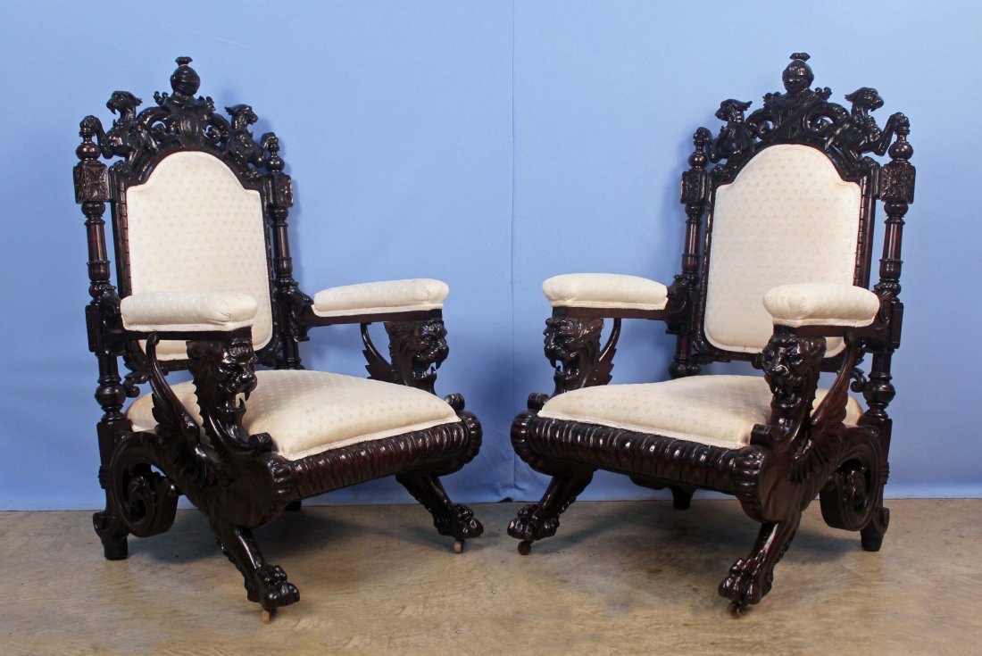 Pair 19th C. Mahogany Winged Griffin Throne Chairs: A pair of 19th Century carved mahogany winged griffin Renaissance Revival armchairs. The gentleman's chair bears winged griffin arm supports with claw feet. The top crest is a knight's helmet above a 