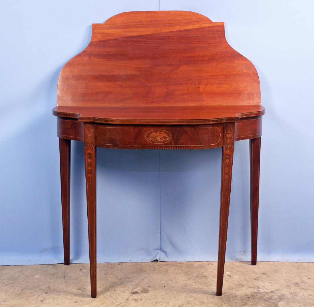 A Hepplewhite Style Inlaid Mahogany Game Table: Hepplewhite Style Mahogany Game Table, Early 20th Century with fine eagle inlay (painted and inlaid). Top edge is double string inlaid and legs have graduated bellflower inlay. 30" H. X 36" W. X 17.75