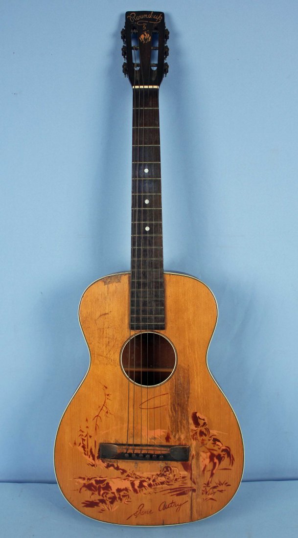 Regal Gene Autry Melody Ranch Guitar, Circa 1940: Regal Gene Autry Melody Ranch Guitar, Circa 1940. Guitar measures 36.5" L. Condition: Guitar has pic wear to scene, scratches to front and back, missing tuning keys and a crack on the side running the