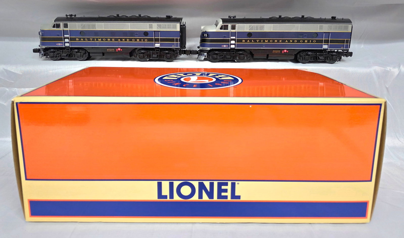 Lionel B&O #115 F-3 A-A Diesel Locomotive: This offering includes a set of two Lionel model F-3 A-A unit style diesel locomotives, prominently featuring the Baltimore and Ohio (B&O) railroad livery. Each locomotive is painted in a striking sch