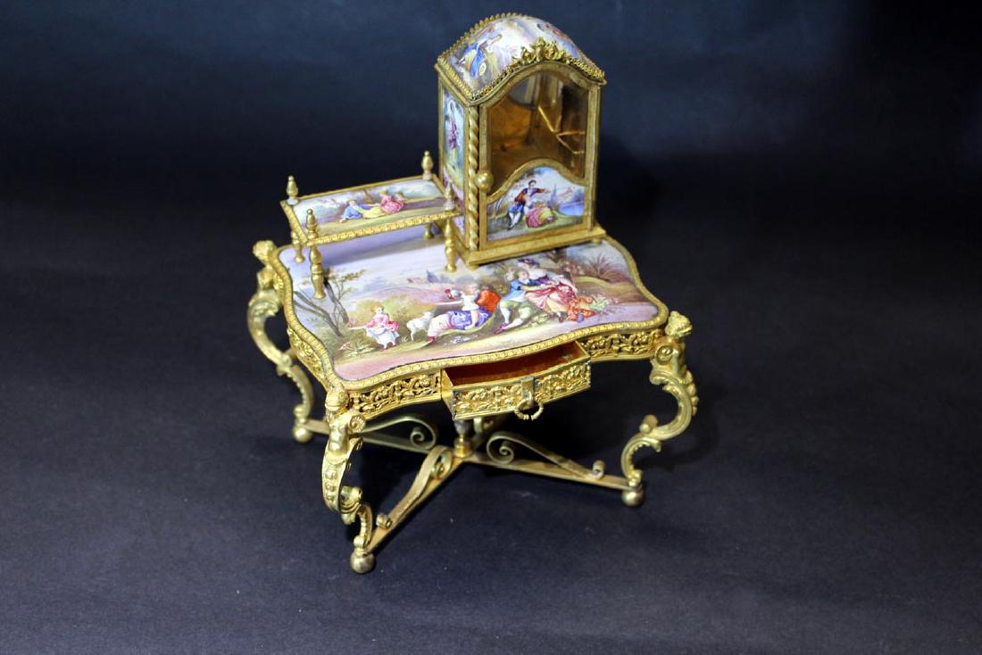 Miniature Viennese Enameled Desk: Unsigned enamel paintings depicting country courting scenes. The upper display cabinet is painted on all four sides with a beveled glass window in the front. The door opens to a single glass shelf and