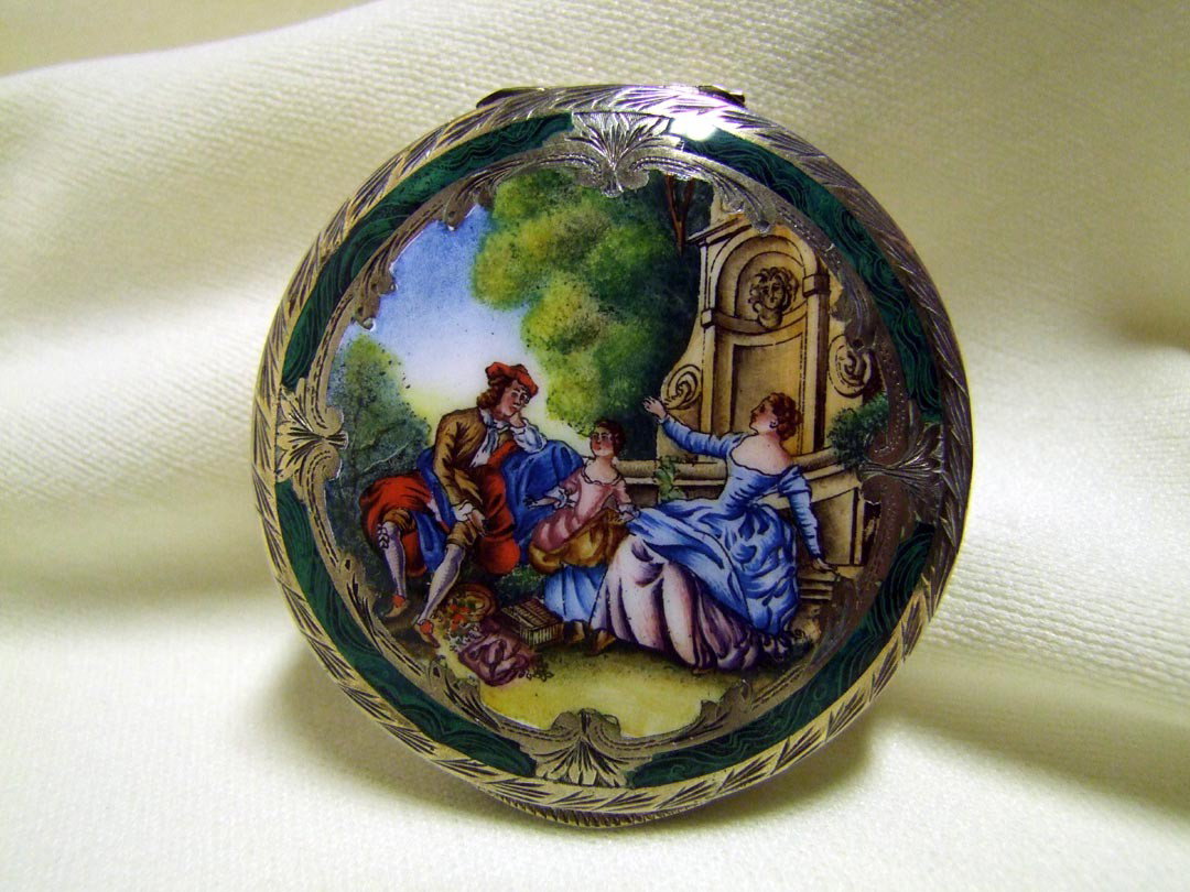 Malachite And Enameled Silver Compact: Marked 800 for European silver with enameled garden scene of a family enjoying a picnic. The side wall and bottom are completely engraved. 2 3/4" in diameter.