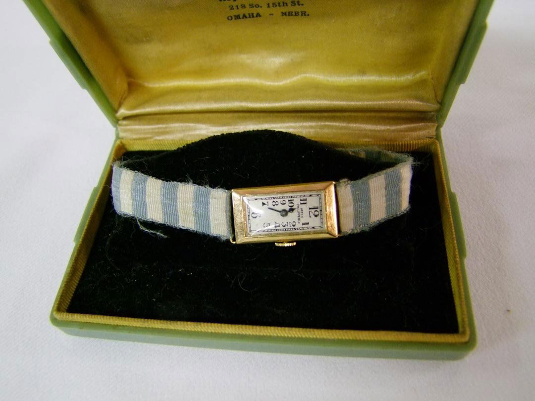 1930s Lady's 18K Patek Philippe Wristwatch: 18K yellow gold watch with ribbon band, stamped 18K on clasp. Rectangular case # 1245 and works # 820112. 1 1/8" long with Arabic numerals. Works. Monogram on back A.M.N., Dubuque.