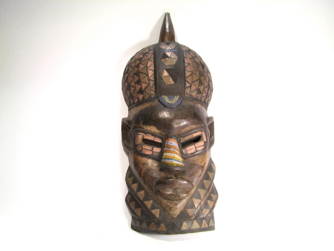 West African Face Mask: Beadwork and copper triangles decorate the mask, 218 pieces of copper are present with 9 missing. Beadwork covers the nose and the center of the forehead. 10 3/4" x 25 1/2" high. The top of the hat sp