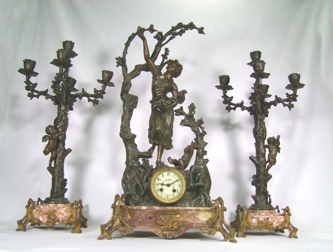 19th Century Clock Set CUEILLETTE de POMMES: Three piece spelter clock set by Geo Maxim signed in the casting. A very pretty young woman picking fruit from the tree with a child at her feet. The original five light candelabra garnitures are in t
