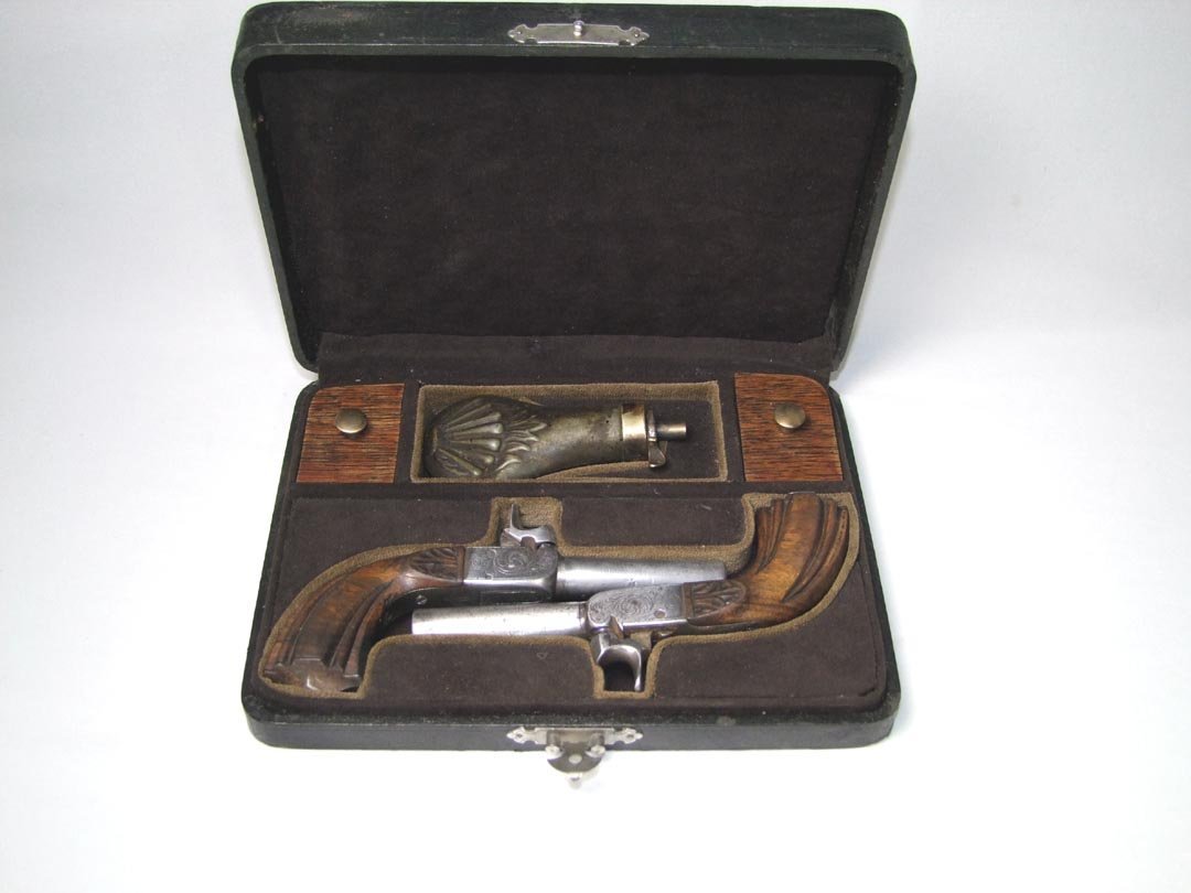 Mid-19th Century English Dueling Pistols: Matched pair of dueling pistols with carved walnut handles, 2 1/2" barrels, folding triggers and engraved. Fitted case with powder flask and compartments for the caps and balls. No Makers Mark found. 