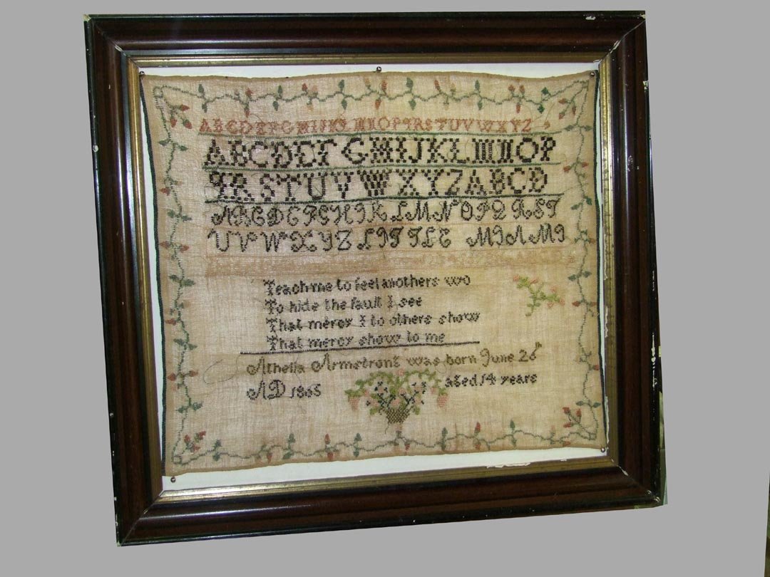 Early 19th Century Sampler: Sampler dated AD 1805 by Athelia Armstrong at the age of 14. Flower basket at the bottom with examples of the alphabet and a poem. Flowering vine border. 19" x 16" high.