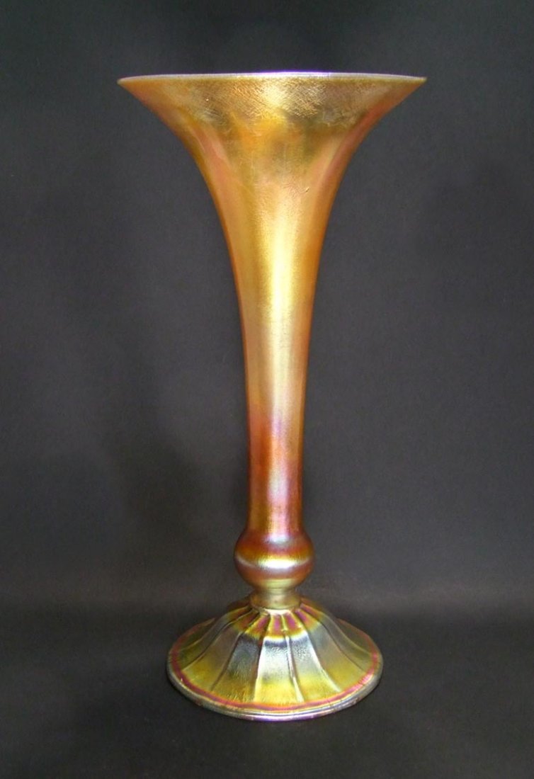 15 1/2" Tiffany Vase: Gold Tiffany vase with bright raspberry highlights signed "L.C.T. 3213A". 7 1/4" diameter trumpet top tapering down to a ball base with inverted ribbed bowl shape foot. Flea bite on the rim is a flaw 