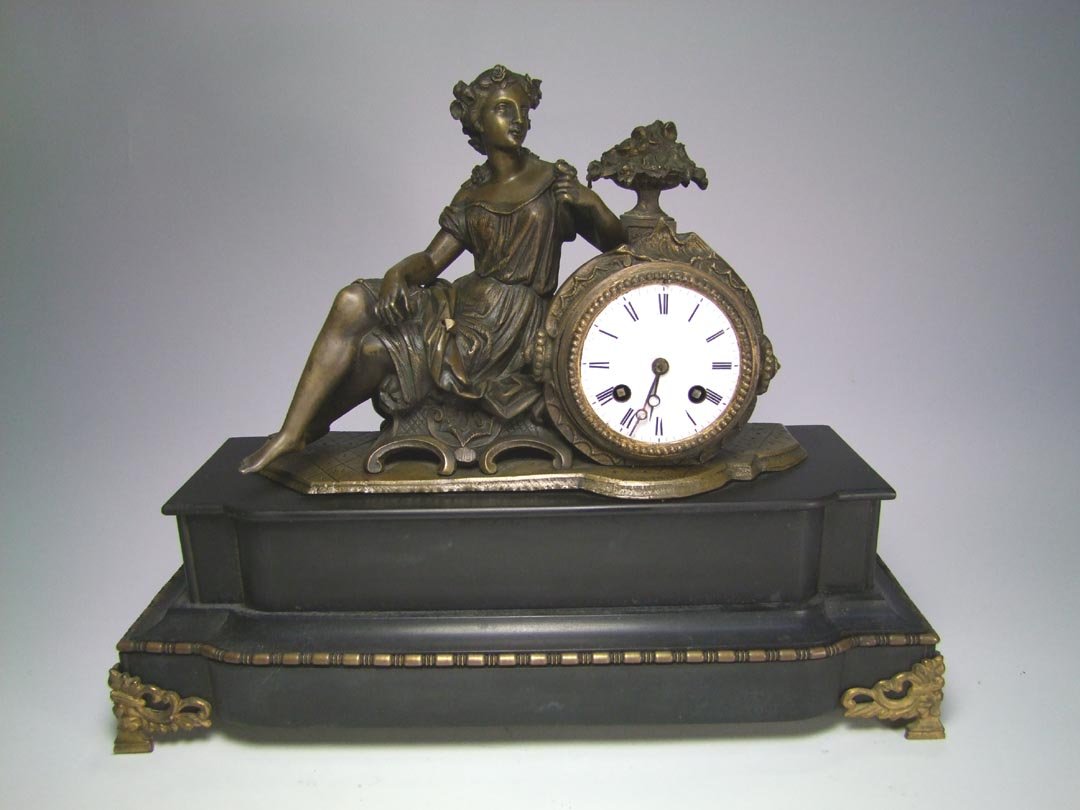 Jappy Freres Statue Clock: Statue of a Grecian woman sitting on a bench next to the porcelain dial. The step back base is made of black granite with bronze trim. 17" x 6" x 13 3/4" high. Suspension wire is missing and a few sma