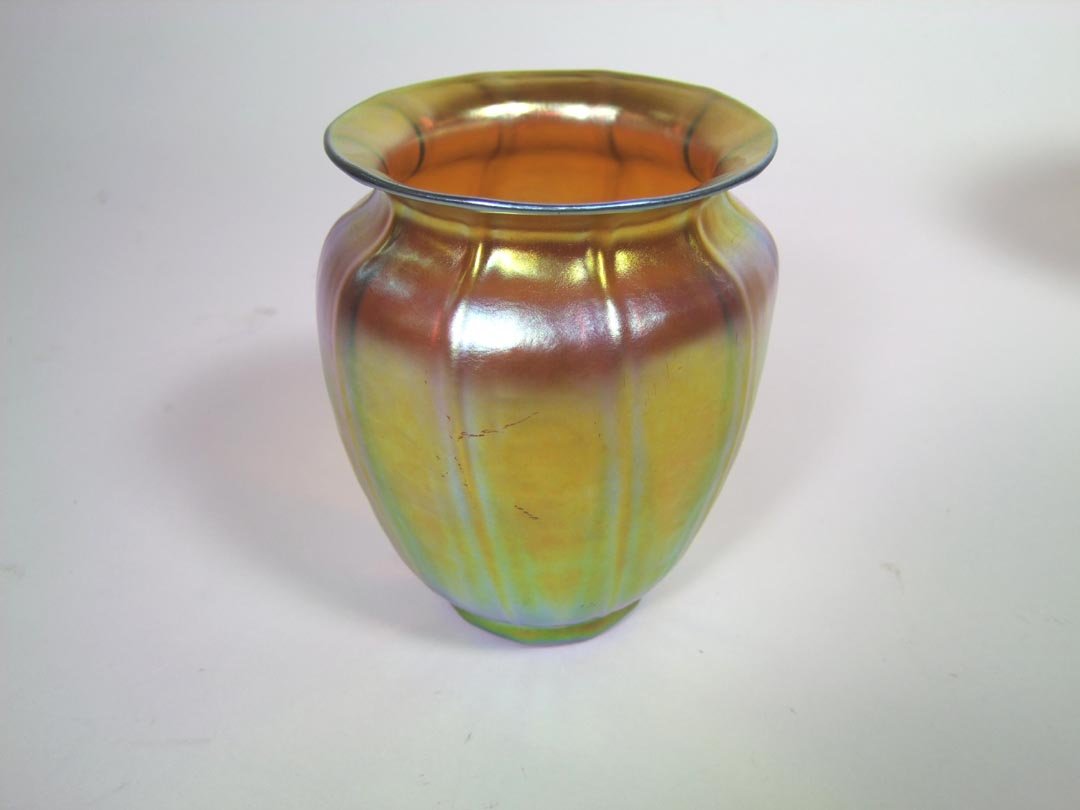 Gold Steuben Vase: Unsigned gold Steuben vase with blue and raspberry highlights. Ribbed body drawn in at the shoulder with a flared top. Light surface scratches. 4 1/4" diameter x 5" high.