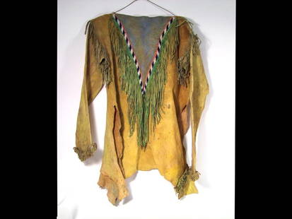 Kiowa War Shirt: 19th century made from brain tanned buffalo hide. Sinew sewn and beaded "V" design on front and back with black and white trade beads. Fringed at the cuffs, shoulder and on the "V" neck. Colored with