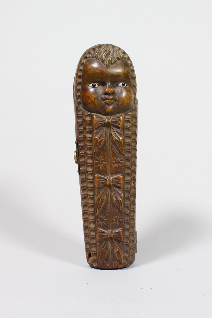Sarcophagus And Pipes: Carved walnut sarcophagus that opens to a shaped compartment to hold two pipe bowls in the shape of faces and one stem. Horseshoe shape snap closure. 6" long.