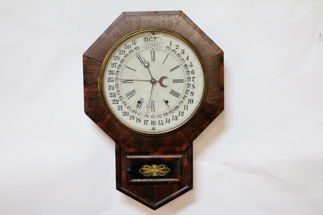 Galusha Maranville Calendar Clock: Rosewood drop octagonal calendar wall clock with openings for month, day and date. Painted over paint loss on the tin dial. Marked "Patented by Galusha Maranville, March 5, 1861". Works. Minor veneer