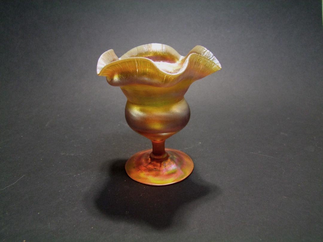 Gold Tiffany Flower Form Vase: Rich gold tones with butterscotch onion skin rim, bulb body raised on an inverted saucer base. Blue and raspberry highlights. Signed L.C.T. 427B. 4 1/2" diameter top x 4 3/4" high. Very good condition
