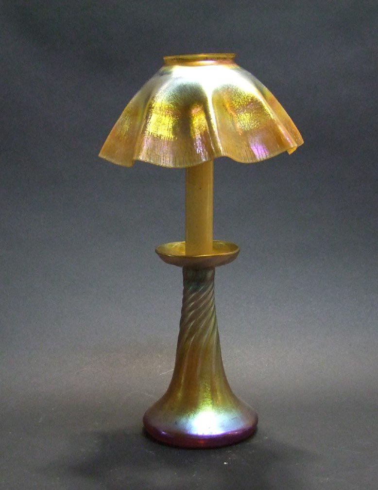 Gold Tiffany Candle Lamp: 7" diameter shade with repaired chip on the upper rim signed L.C.T. 6 3/4" gold candlestick base with spiraling ribs signed L.C.T. 7" candle insert.