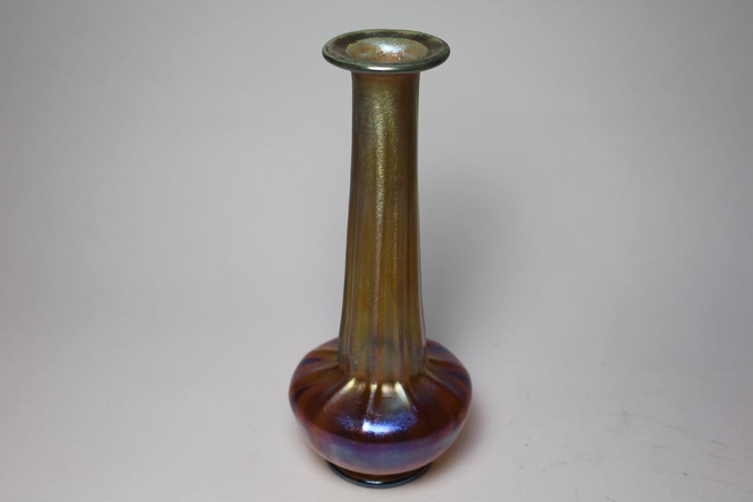 Gold Tiffany Vase: Ribbed vase with bulbous base, elongated neck and 2" diameter flared top signed 1834 L.C.Tiffany-Favrile. 8" high in very good condition with no chips, cracks or repairs. Purple highlights.