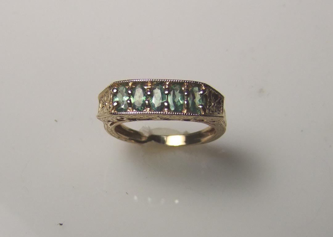 14K Gold Alexandrite Ring: Lady's 14K yellow gold genuine alexandrite ring. This ring has engraved sides and shank set with 5 matched 5 x 3mm oval greenish alexandrite stones across the center. Weighs 4.9 grams. Appraised at Er