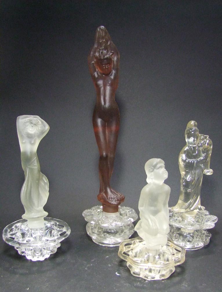 Four Steuben Flower Frogs: Glass flower frogs with figural inserts: 8" frosted semi nude woman with her hands up to her hair (may not be Steuben); 13" frosted amber bathing beauty; 6 1/2" frosted nude girl; 8" clear Chinese wom