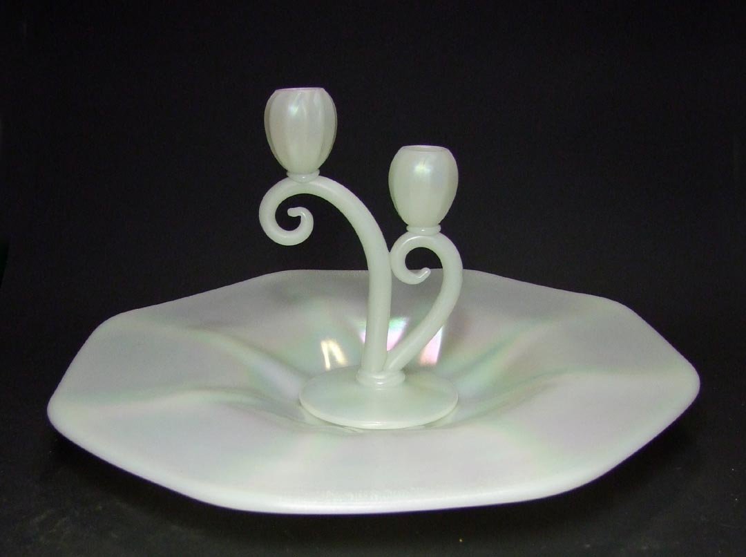 Two Pieces Steuben Ivrene: Duo arm candle holder 4 1/4" diameter base x 8" high. 16 3/4" diameter charger with 8 ribs from the center out into the edge original paper Steuben label. Both pieces unsigned and in very good conditi