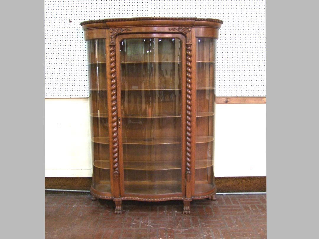1890s Oak China Cabinet: Quarter sawn oak china cabinet with serpentine glass door and curved sides. Winged griffins flanking the door and applied over 3/4 spiral columns down to feather carving. Egg and dart trim at the base