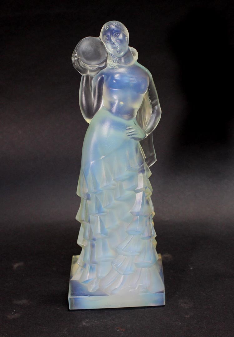 11" Sabino "L'Espagnole" Argentina Figurine: Opalescent figure of a woman wearing a ruffled dress holding a tambourine up to her face. Signed in script on the side. Fleabite on the edge next to her exposed foot.