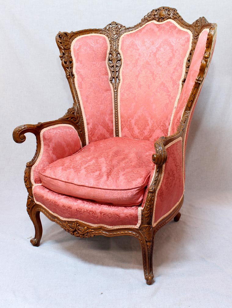 2nd Quarter 20th Century Chair: Fancy wingback chair with pierce carved back, four head medallions and down filled cushion. Very good condition and ready for use. 31 1/2" wide at arm fronts x 47" high at back.