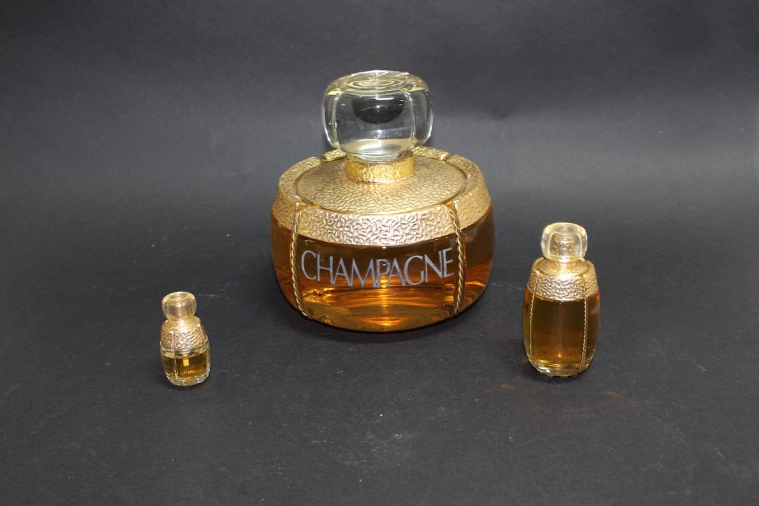 Yves Saint Laurent Champagne Factice: 6" diameter x 6 1/2" high factice dummy with two spray bottles, 3 3/4" and 2 1/4" high. All in very good condition.
