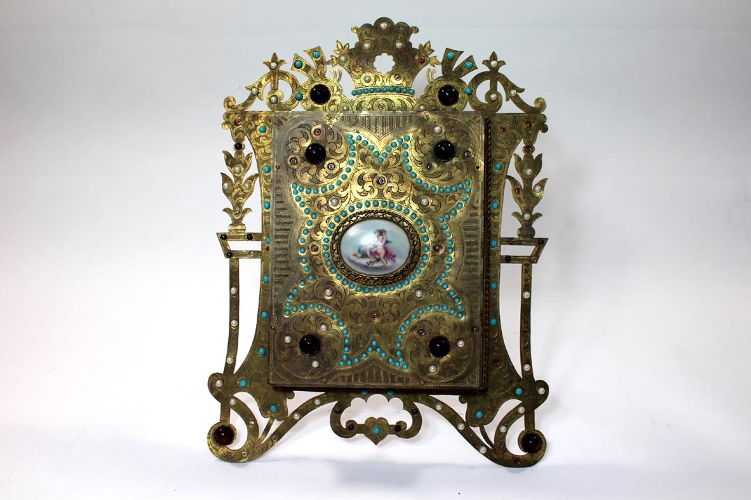 Ornate 19th Century Trifold Mirror: Easel back jeweled brass frame with round porcelain medallion set in the center front. Opens to 3 mirrors for shaving or vanity purposes. 11 1/2" x 15 1/4" high. Also has ring on the back to hang on t