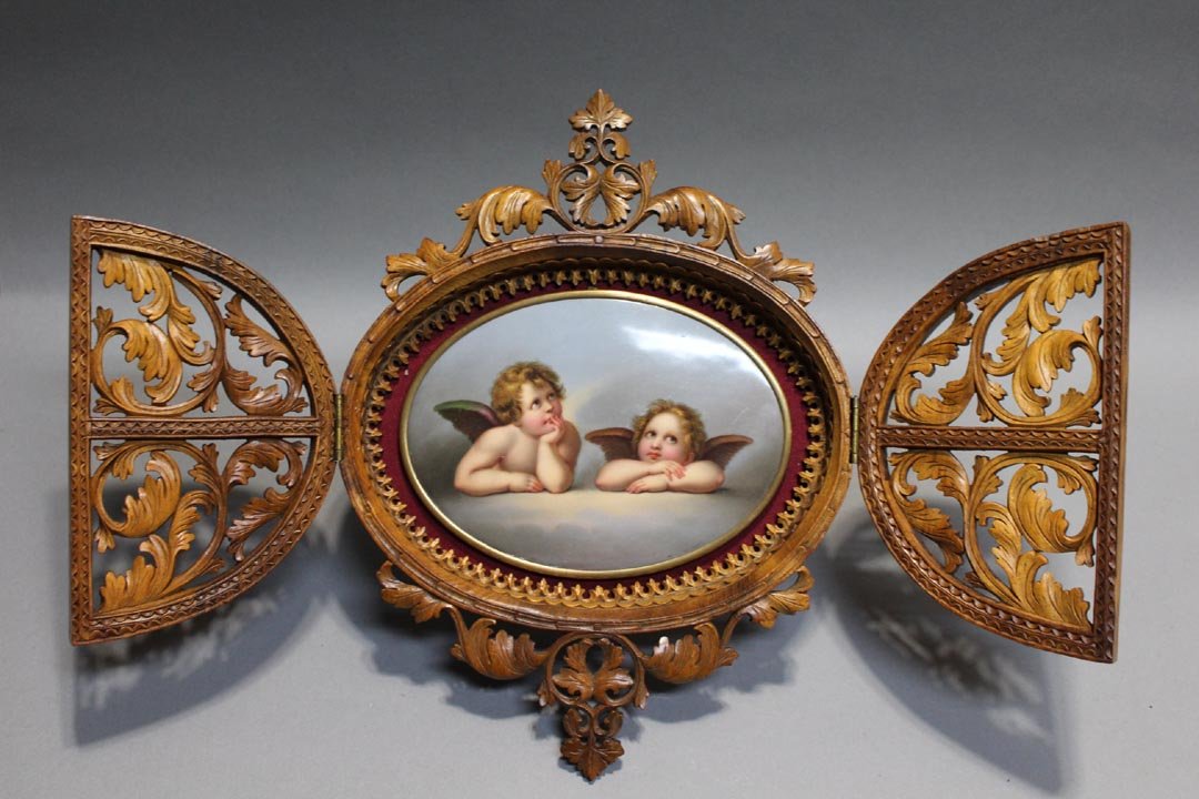 Outstanding Carved Framed Painting: Italian Renaissance style walnut frame with hinged 2-part pierce carved doors that open to an oval painting on porcelain of winged cupids. Painting measures 6 1/4" x 4 3/4" in the very detailed frame