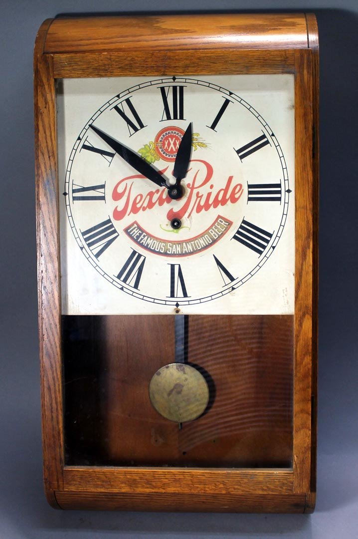 "Texas Pride" Advertising Clock: Oak case wall clock with paper Seth Thomas label on the back and tin advertising dial. 13 3/4" x 26" high. Works