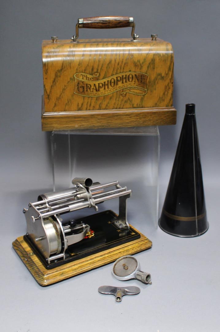 The Gramophone Cylinder Player: Key wind wax cylinder player with graphics on the oak hood stating The Gramophone And Columbia Records Were Awarded The Grand Prize At The Paris Exposition 1900 And St. Louis Exposition 1904. Producer