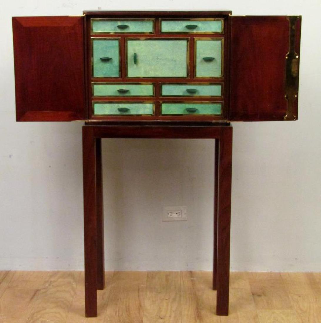 French Art Deco Shagreen Fronted Cabinet: Mahogany cabinet with shagreen inlay escutcheons and top, on a high leg stand. Eight interior drawers and one door of shagreen fronts and brass trim with green handles. High leg stand likely not origi