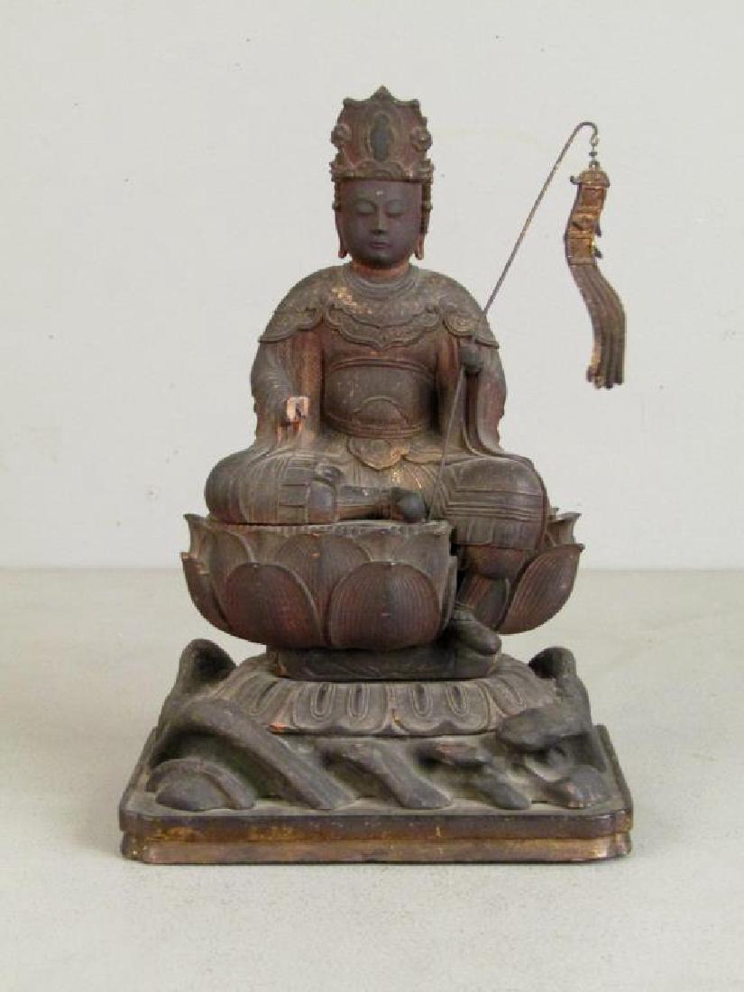 Chinese Carved Wood Seated Buddha/Bodhisattva: Seated, holding pennant and with one leg over lily pad base. Carved removable plate. 6.5"W X 4"D X 11"H