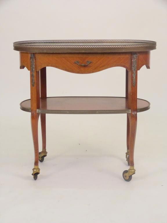 French 2 Tier Rolling Serving Cart: Oval galleried marble top with one inlaid drawer, ending in castors. 18W X 16 1/2D X 27 tall. 8 East 83rd Street Estate