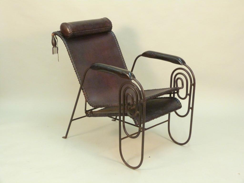 Mid-Century / Art Deco Iron & Leather Lounge Chair: Leather tied leather upholstery. Wrought iron frame with pull out foot rest. Wood mounted arm rests and carved tassels. Very solid condition. 24W X 39"D X 36"H. (52"D open). (Estate of Peter Jennings)