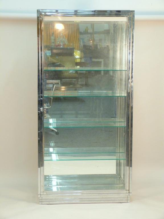 Tall Chrome Display Cabinet: Mirror back and base. Illuminated top. Slight pitting. Four shelves and one mirrored shelf. 38 W X 13" D X 77 1/2" H"